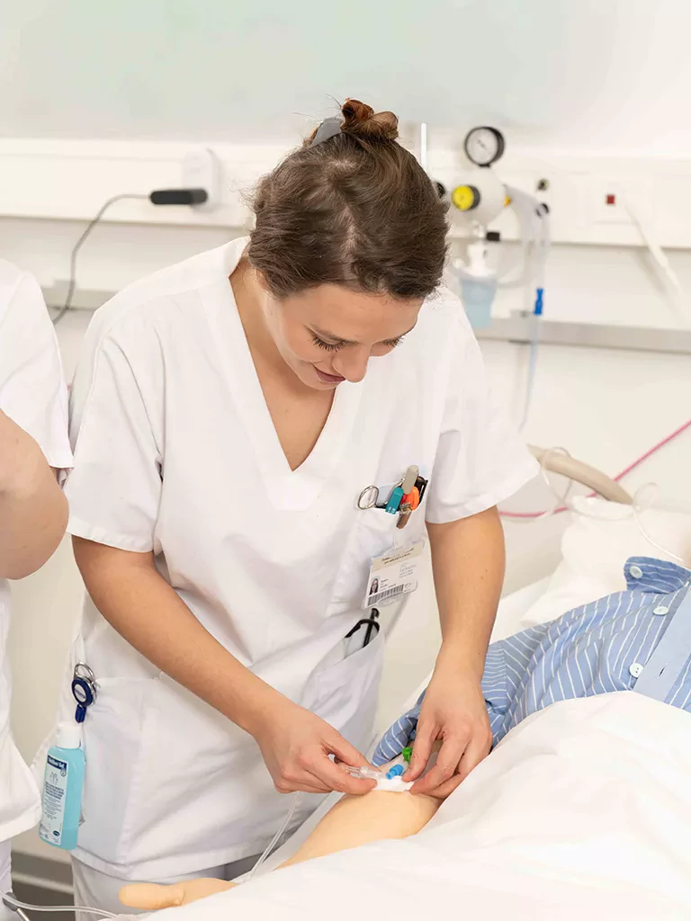 une étudiante infirmière poste une perfusion sur le bras d'un mannequin