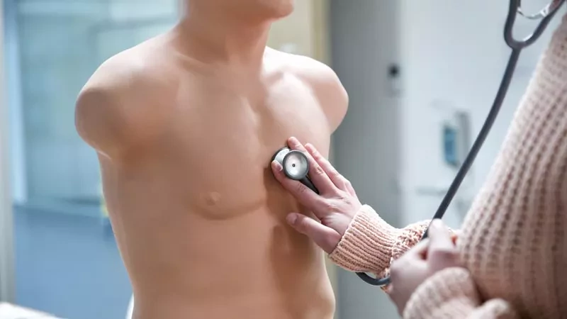 Main avec stéthoscope sur faux torse