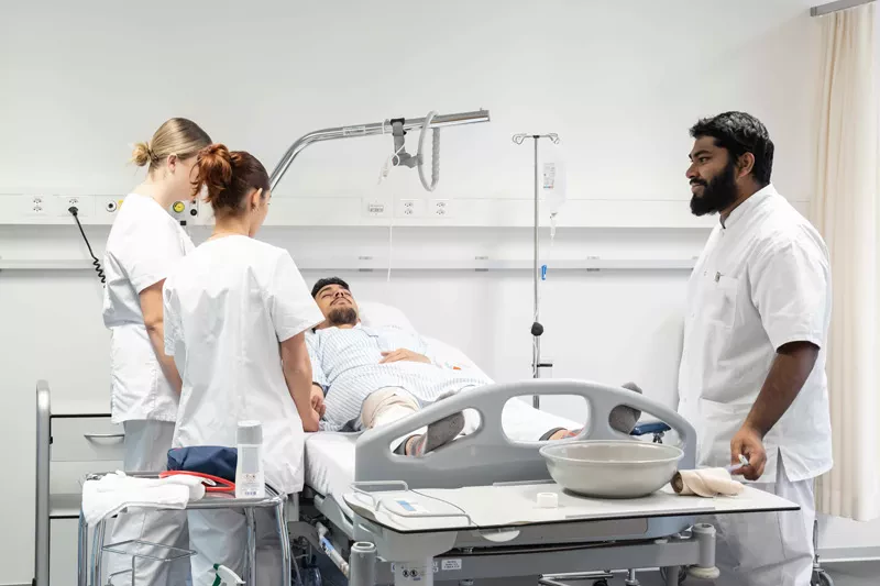Etudiants soins infirmiers autour d'un lit de l'hôpital simulé